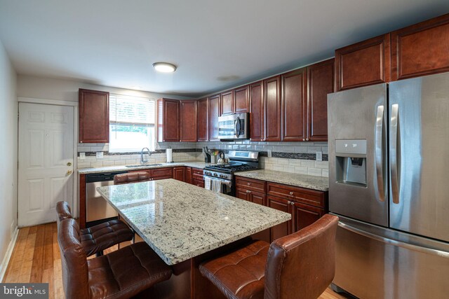 1531 Swain St, Philadelphia, PA 19130 - kitchen with appliances with stainless steel finishes, a sink, a kitchen bar, light wood-type flooring, and decorative backsplash