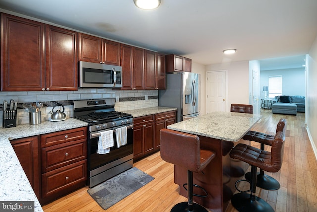 1531 Swain St, Philadelphia, PA 19130 - kitchen featuring appliances with stainless steel finishes, a breakfast bar, light wood-style flooring, and decorative backsplash
