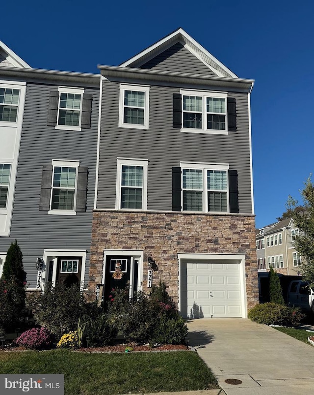 view of front of property featuring concrete driveway, a garage, and stone siding