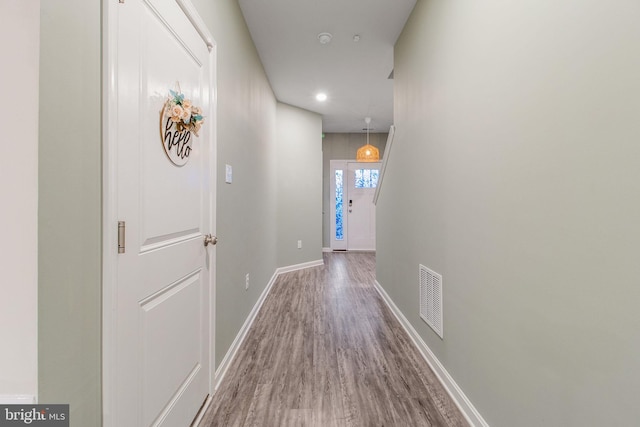 corridor with wood finished floors, baseboards, and recessed lighting