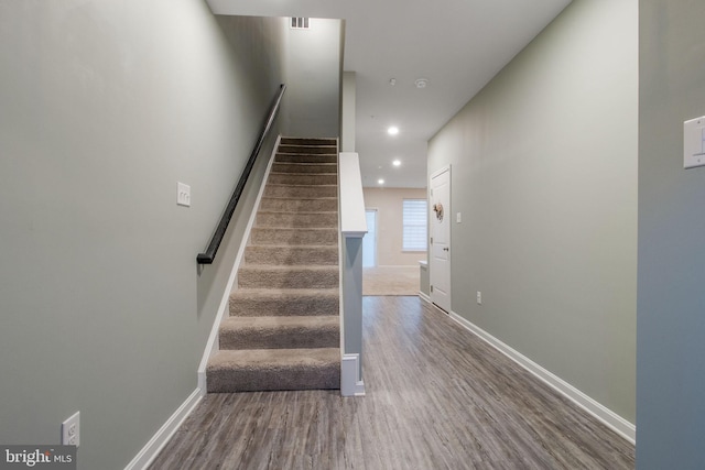 stairs with wood finished floors, recessed lighting, and baseboards