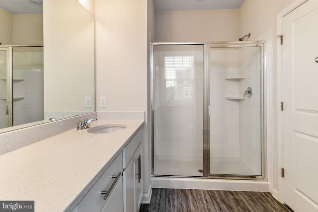 bathroom with wood finished floors, a shower stall, and vanity