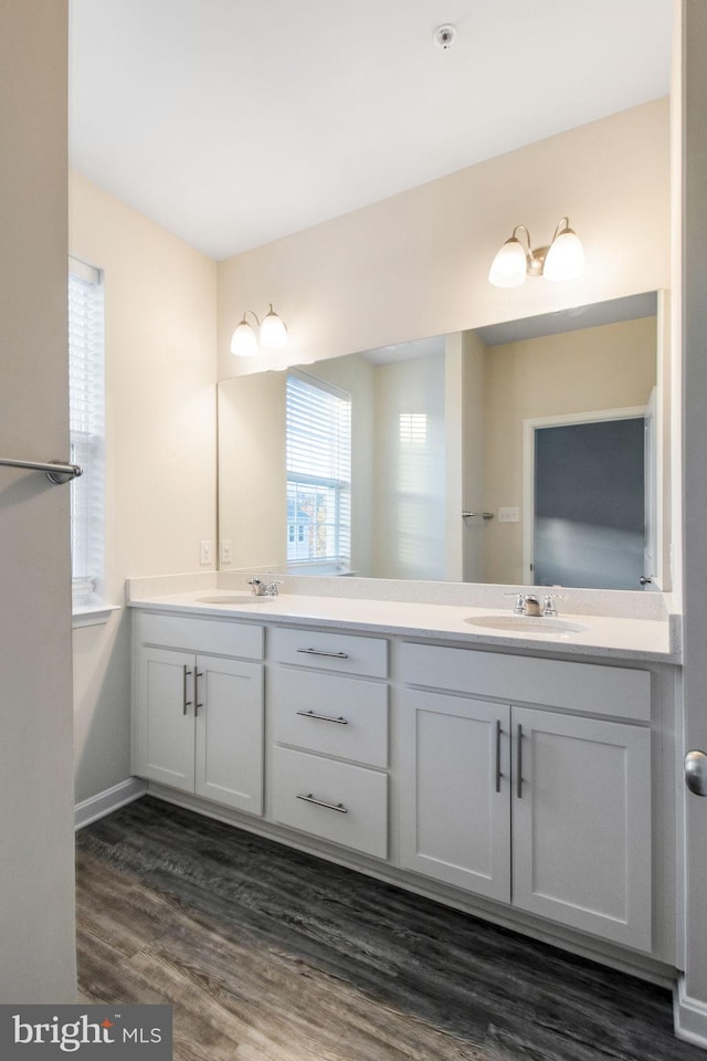bathroom with double vanity, wood finished floors, and baseboards