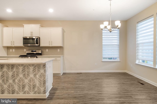 kitchen featuring stainless steel appliances, light countertops, decorative backsplash, a chandelier, and plenty of natural light