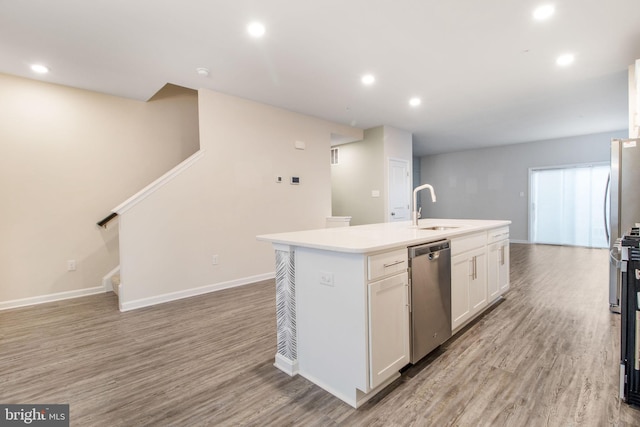 kitchen with dishwasher, a sink, a center island with sink, light wood finished floors, and white cabinets