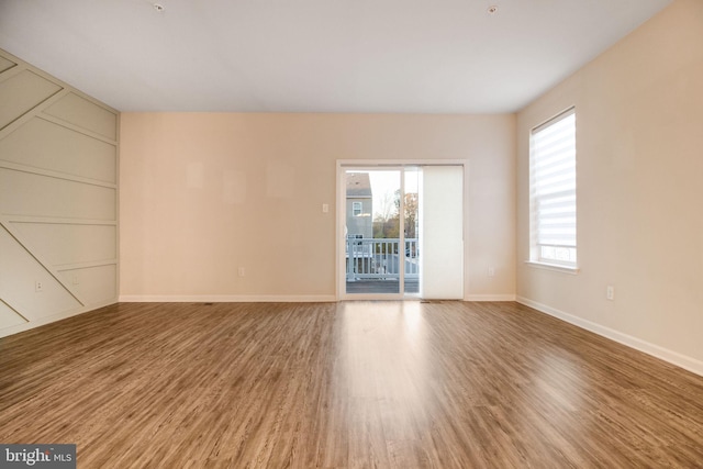 unfurnished room featuring wood finished floors, baseboards, and built in shelves