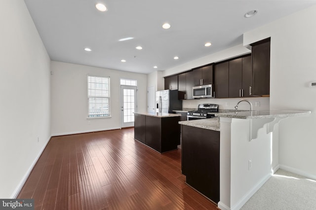 kitchen with stainless steel appliances, baseboards, a center island, recessed lighting, and dark wood-style floors