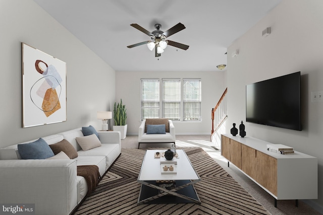 carpeted living area featuring stairway, a ceiling fan, and baseboards