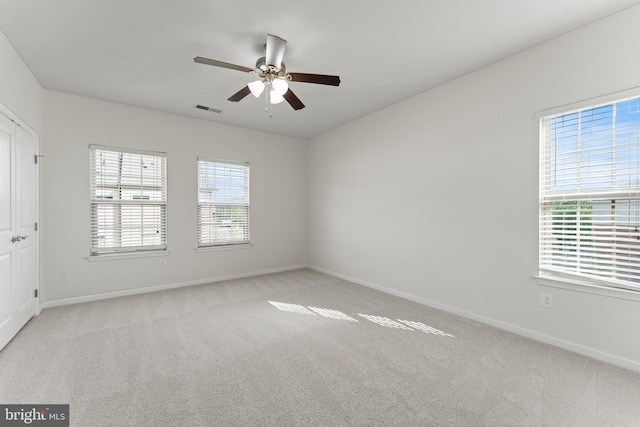 carpeted spare room with healthy amount of natural light, ceiling fan, and baseboards