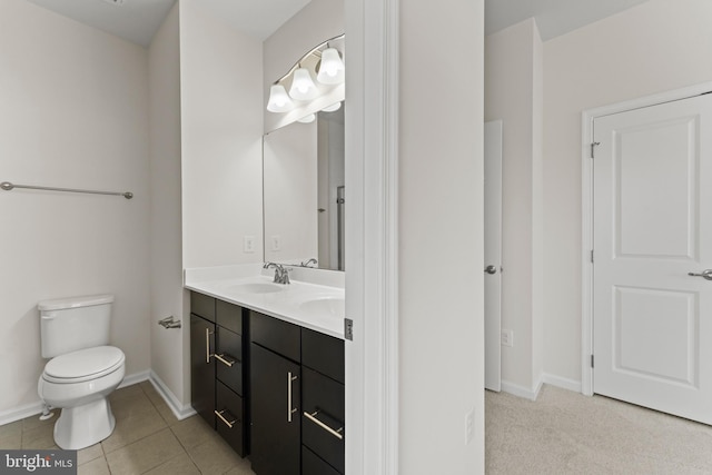 bathroom featuring toilet, double vanity, baseboards, and tile patterned flooring
