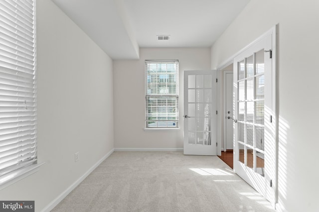 carpeted empty room featuring french doors and baseboards