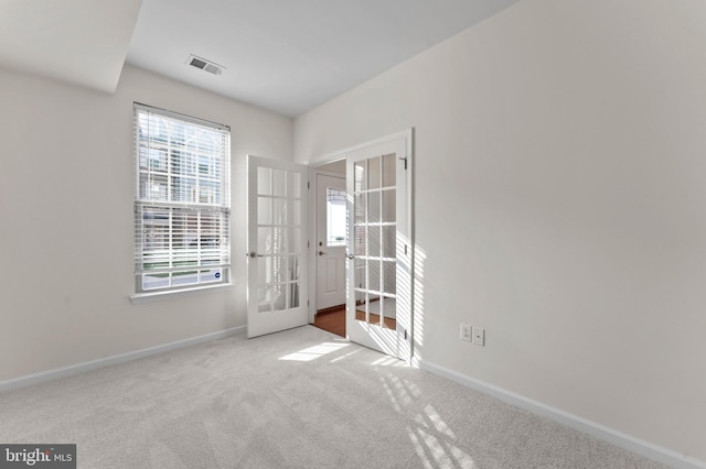 carpeted empty room with french doors and baseboards