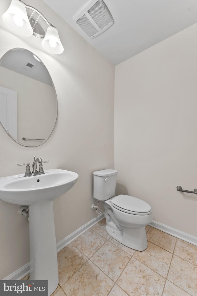 half bathroom with toilet, tile patterned floors, and baseboards