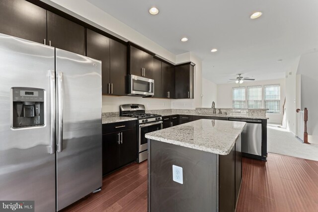 kitchen featuring stainless steel appliances, a sink, a peninsula, a kitchen island, and recessed lighting