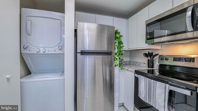 3101 Boardwalk Unit 1206-2, Atlantic City, NJ 08401 - kitchen with appliances with stainless steel finishes, stacked washer / dryer, white cabinetry, and light stone counters