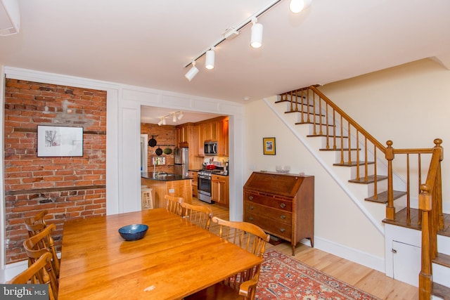 256 N Union St, Lambertville, NJ 08530 - dining room with rail lighting, light wood-style floors, stairway, a wall unit AC, and brick wall
