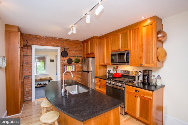 256 N Union St, Lambertville, NJ 08530 - kitchen featuring stainless steel appliances, a sink, light wood-type flooring, brick wall, and an island with sink