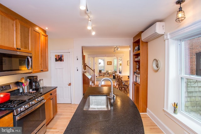256 N Union St, Lambertville, NJ 08530 - kitchen with appliances with stainless steel finishes, a sink, a wall unit AC, dark countertops, and light wood-type flooring