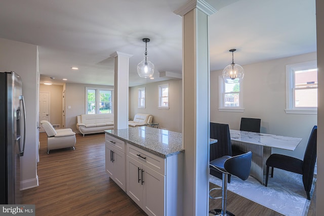 3958 Oakford Ave, Baltimore, MD 21215 - kitchen featuring ornate columns, dark wood-type flooring, light stone countertops, white cabinets, and stainless steel fridge with ice dispenser