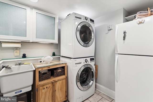 430 M St SW Unit N-609, Washington, DC 20024 - washroom featuring stacked washing machine and dryer, cabinet space, light tile patterned floors, and baseboards