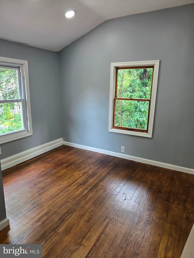 empty room with hardwood / wood-style floors, healthy amount of natural light, vaulted ceiling, baseboards, and recessed lighting