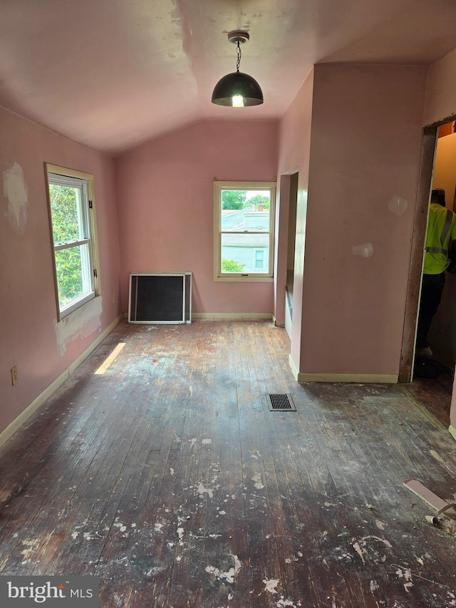 unfurnished living room with hardwood / wood-style flooring, vaulted ceiling, healthy amount of natural light, and baseboards