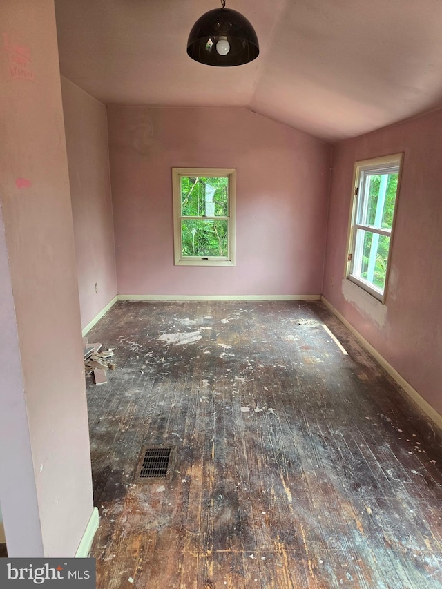 empty room featuring hardwood / wood-style floors, vaulted ceiling, and baseboards