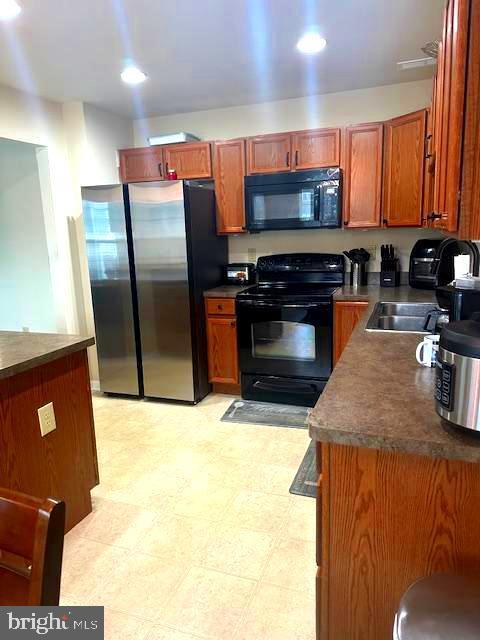 88 Fuzzy Tail Dr, Ranson, WV 25438 - kitchen with black appliances, dark countertops, light flooring, recessed lighting, and brown cabinetry