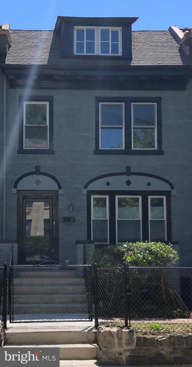 townhome / multi-family property with brick siding, a fenced front yard, and a gate