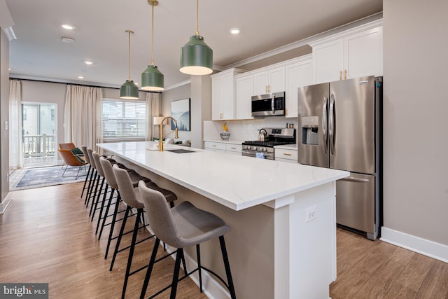 kitchen featuring stainless steel appliances, a sink, a spacious island, white cabinets, and decorative backsplash