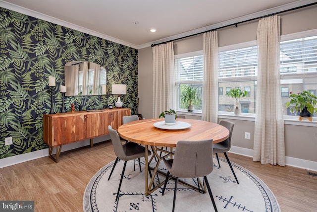 dining space featuring wallpapered walls, baseboards, ornamental molding, light wood-style flooring, and plenty of natural light