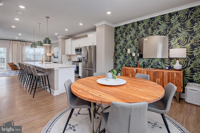 dining room with wallpapered walls, crown molding, light wood-style floors, recessed lighting, and baseboards