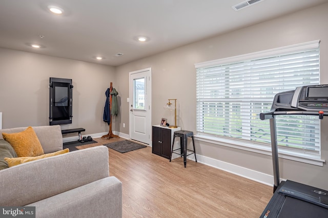 exercise area featuring light wood finished floors, baseboards, and recessed lighting