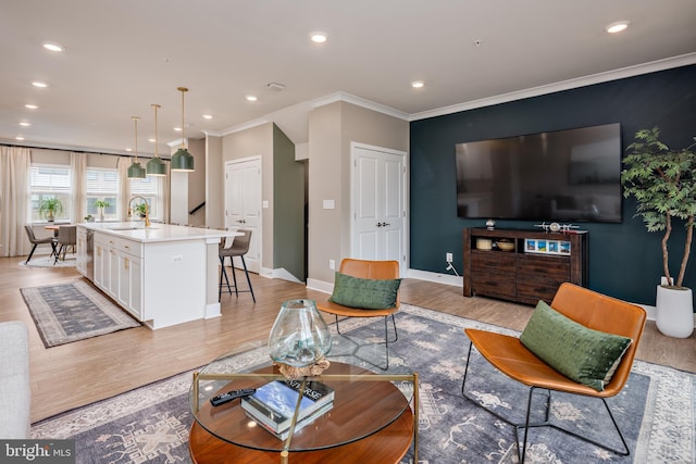 living room with light wood-style flooring, recessed lighting, crown molding, and baseboards