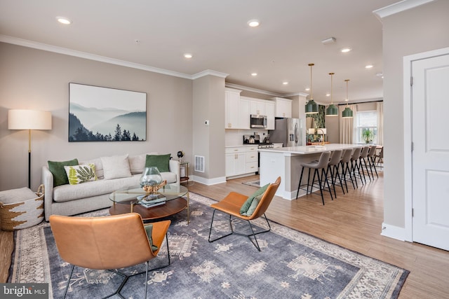 living area with light wood-type flooring, ornamental molding, recessed lighting, and baseboards