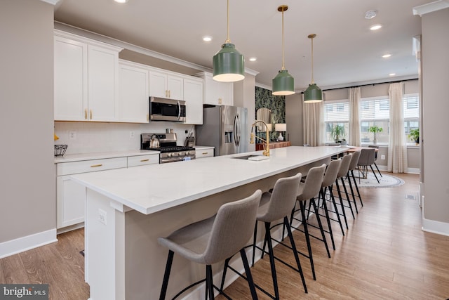 kitchen featuring appliances with stainless steel finishes, a large island, baseboards, white cabinetry, and recessed lighting