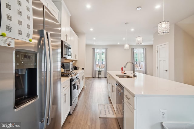 1724 Atlas Dr, Frederick, MD 21702 - kitchen featuring stainless steel appliances, a sink, white cabinetry, light wood-style flooring, and a kitchen island with sink