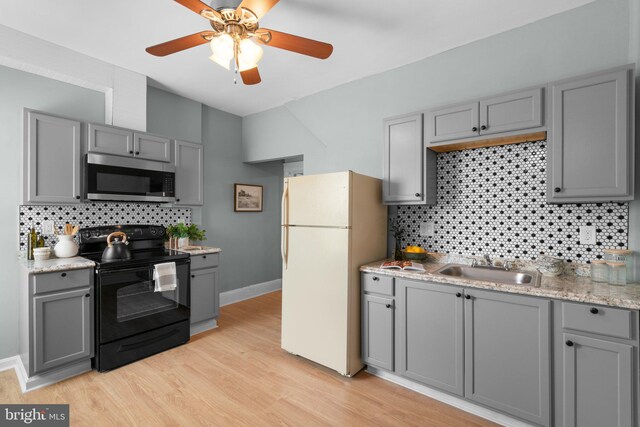 2719 Wilkens Ave, Baltimore, MD 21223 - kitchen featuring stainless steel microwave, black range with electric stovetop, gray cabinetry, freestanding refrigerator, and a sink