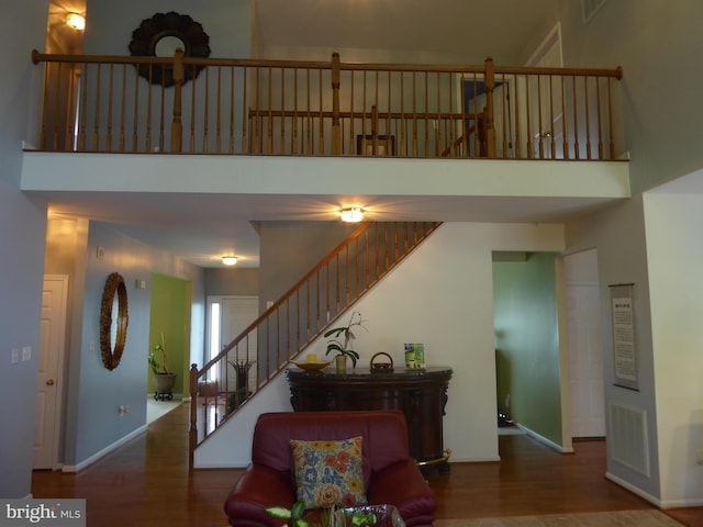 living area featuring a high ceiling, wood finished floors, baseboards, and stairs