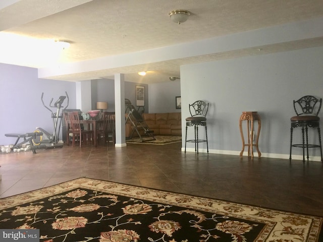 finished basement featuring baseboards, tile patterned floors, and a textured ceiling