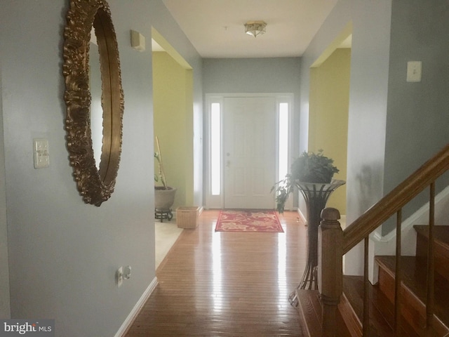 entrance foyer featuring wood-type flooring, stairway, and baseboards