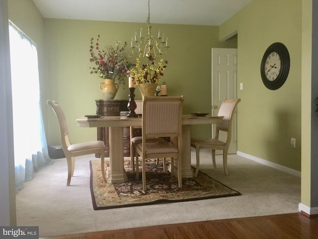 carpeted dining space with a chandelier, baseboards, and wood finished floors