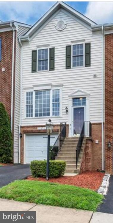 multi unit property with brick siding, asphalt driveway, and an attached garage