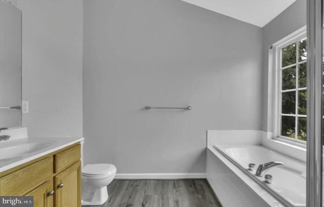 bathroom featuring wood finished floors, a bath, vanity, toilet, and baseboards