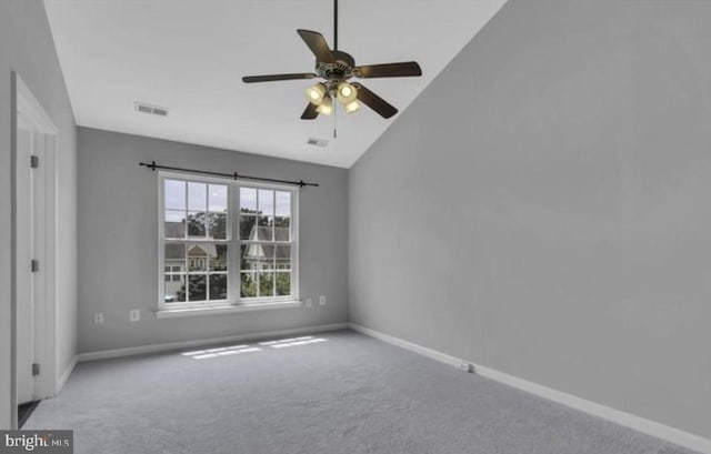 carpeted empty room featuring baseboards, vaulted ceiling, and a ceiling fan