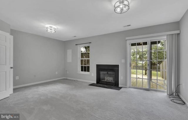 unfurnished living room featuring carpet floors, baseboards, and a fireplace with flush hearth