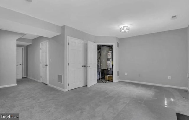 carpeted empty room featuring baseboards and gas water heater