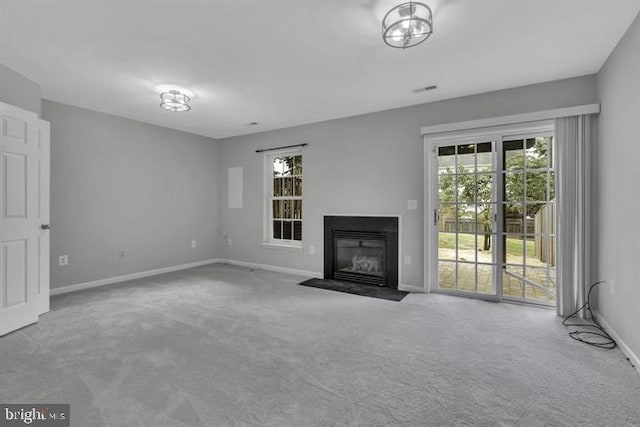 unfurnished living room with carpet floors, baseboards, and a fireplace with flush hearth