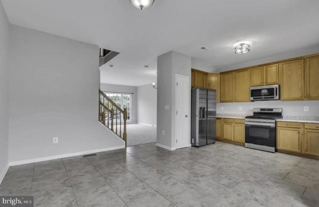 kitchen featuring stainless steel appliances, light countertops, open floor plan, and baseboards