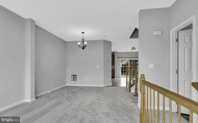 spare room with a chandelier, carpet floors, and baseboards